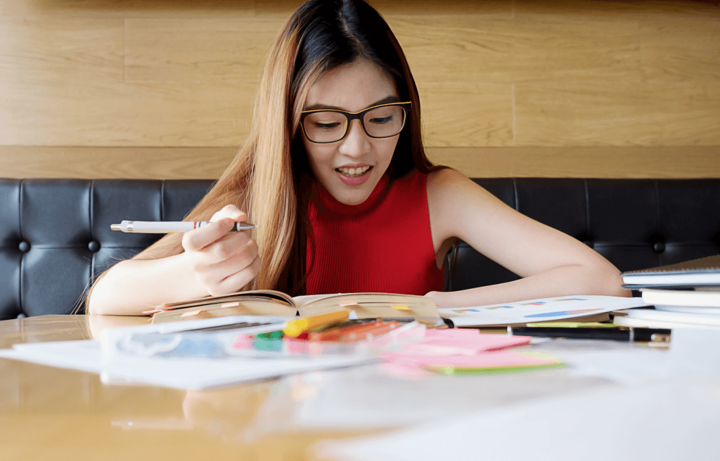 asian girl in red top studying with glasses