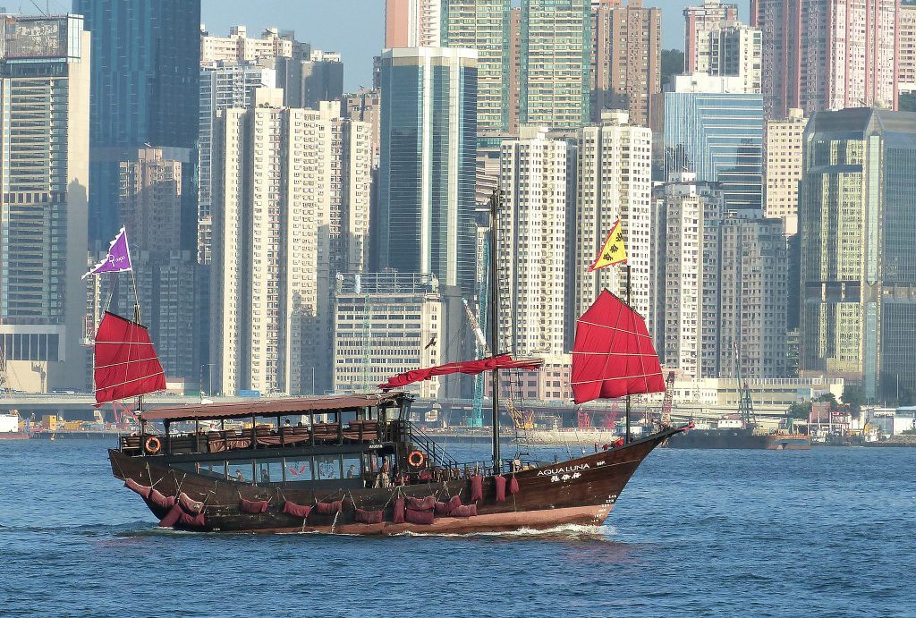 junk boat with red flag, hong kong skyline, tst harbour